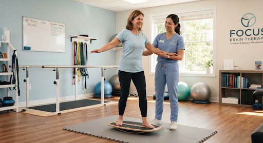 A patient standing on a balance board supported by a physical therapist in a bright, modern clinical therapy room